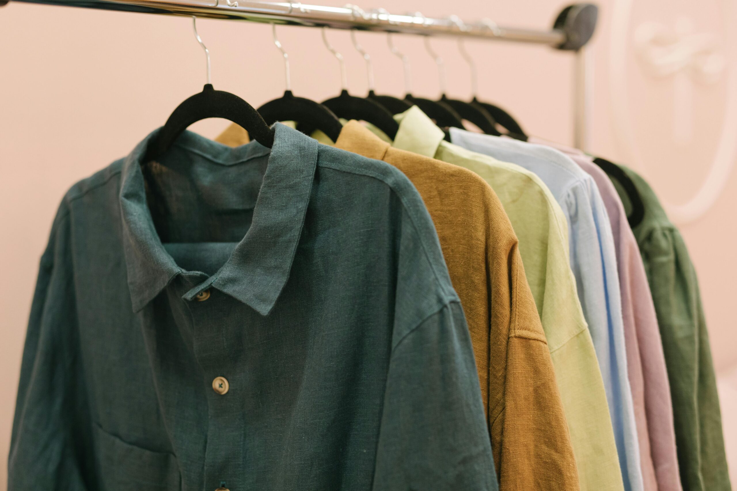 A collection of colorful shirts hanging on a rack indoors in soft lighting.